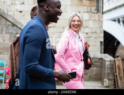 A group of businesspeople walking home from work together. The main focus is on one businesswoman smiling and laughing at the two other men. Stock Photo