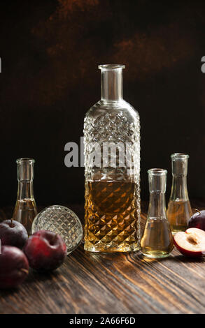 Rakia or rakija traditional Balkan fruit brandy. Plum brandy slivovica in a glass which is called cokanj and bottle on a wooden table Stock Photo