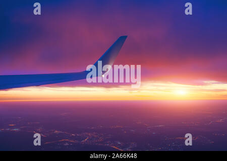 Sunset sky from an airplane side wing view of the horizon and city lights Stock Photo