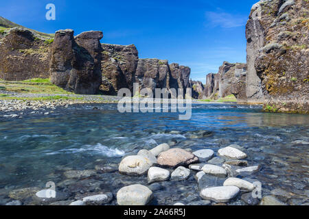 Fjadra River flowing through rocks against cliffs in Fjadrargljufur canyon on sunny day, South Iceland, Iceland Stock Photo