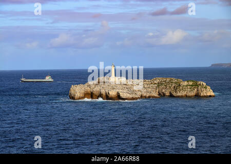 Cargo ship leaving the Santander port by lighthouse in the Mouro Island, Santander (Spain) Stock Photo