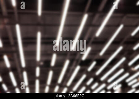 Abstract blurred white neon led light lamp stripes on mall ceiling or roof. Perspective striped futuristic loft modern background Stock Photo