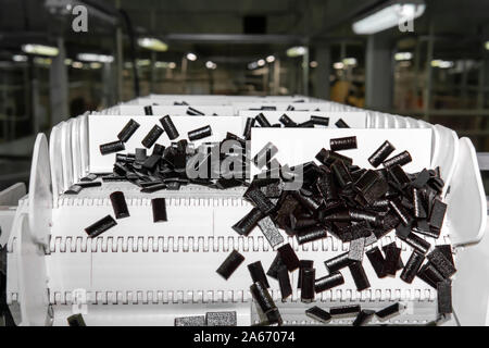 sliced fruit pastilles move on the conveyor of a confectionery factory against a blurry shop background Stock Photo