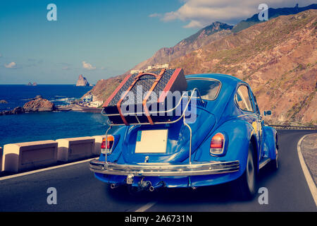 Retro car with luggage on the roof rack on the coastal road. Travel, vacation concepts.retro, vintage color Stock Photo