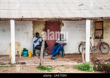Two Gambian men chatting outside a roadside house in Senegambia. Stock Photo