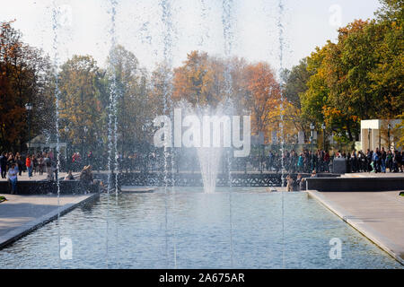 Fountain in a city park, close up. A fountain against a background of trees covered with autumn foliage and people walking in the park. Rest zone. Stock Photo