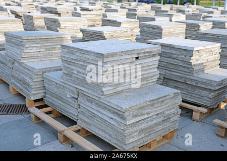 Gray concrete blocks on wooden pallets. Concrete paving slabs. Materials for laying the surface of sidewalks and squares. Stock Photo