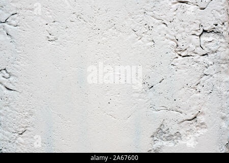 Texture of a white painted wall with cracks and bumps. Light gray stone texture background. Stock Photo