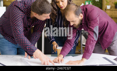 Creative agency meeting where team of architects and designers are talking over blueprints Stock Photo