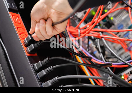 Male IT Engineer Removing Power Cable From Outlet in Datacenter Stock Photo