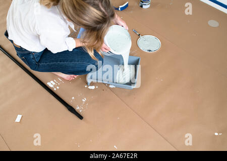Woman pouring white paint in a bucket Stock Photo