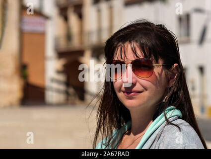 Portrait of a smiling young large size woman in glasses against the street on a sunny day, close-up Stock Photo