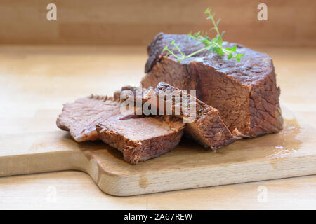 Slices of roast beef, ready braised in red wine with thyme garnish on a wooden table for a festive dinner like boeuf bourguignon, copy space, selected Stock Photo