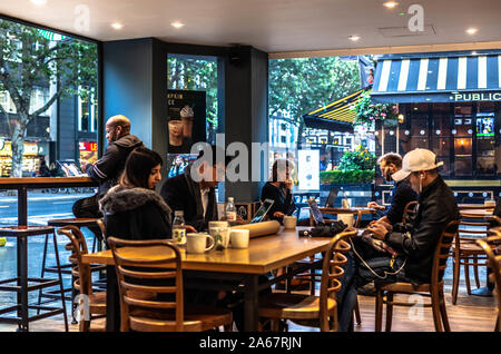 Multicultural group of people using laptops inside a Starbucks coffee shop, London, England, UK. Stock Photo