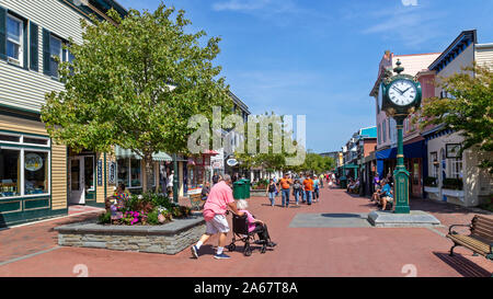 Shoppers, friends, tourists walk in an outdoor mall, talking, laughing and walking in the stores on a beautiful Day. Stock Photo