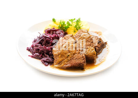 braised beef with potatoes, red cabbage and parsley garnish on a plate, isolated on a white background, selected focus, very narrow depth of field Stock Photo