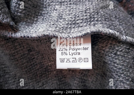 Wrong side of a gray dress made of wool, the composition is specified: cotton, polyester and lycra. Fabric composition clothes label on gray texture b Stock Photo