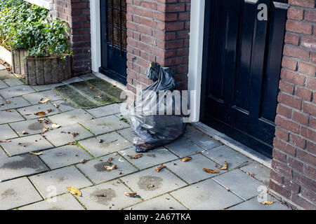 Garbage bag near a front door in a neighbourhood, ready for pick up Stock Photo