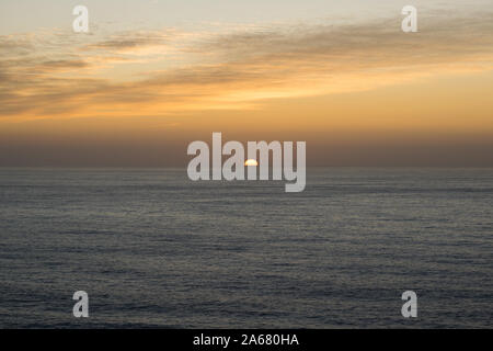 Beautiful sunset with orange colors in the sky and the sun hiding in the sea on the horizon Stock Photo