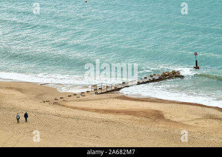 A middle aged couple walk near a groyne on the sandy beach of the English channel at Bournemouth, England. Stock Photo