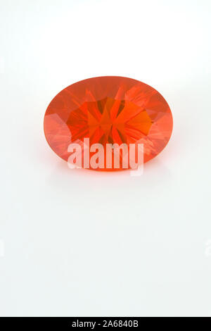 A large oval faceted mexican fire opal shown on a white background. The stone is mostly orange in color. Stock Photo