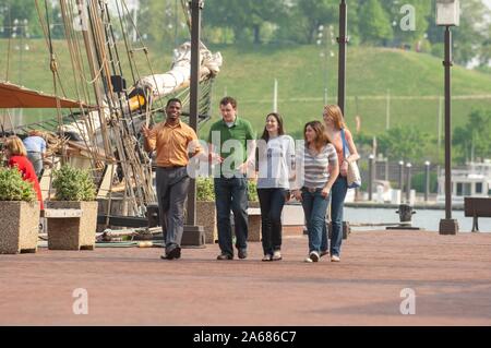Johns Hopkins University students, on a sunny day, walking on a brick wharf next to a historic ship docked in the Inner Harbor area, Baltimore, Maryland, May, 2008. From the Homewood Photography Collection. () Stock Photo