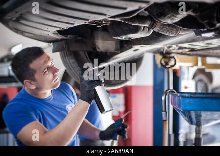 Car master mechanic repairer lubricates the screws with a machine parts cleaner oil dirt grease aerosol spray for lubrication in auto vehicle workshop Stock Photo