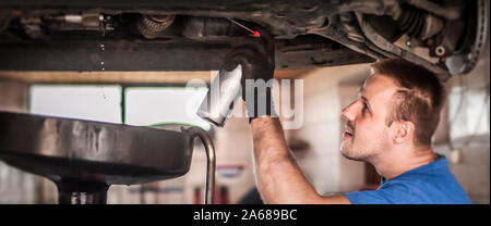 Car master mechanic repairer lubricates the screws with a machine parts cleaner oil dirt grease aerosol spray for lubrication in auto vehicle workshop Stock Photo