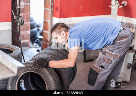 Car master mechanic vulcanizer replaces and changes old with new tires in auto vulcanizing and vehicle service workshop Stock Photo