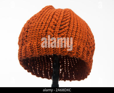 This orange pumpkin color knitted hat is winter fashion accessory object isolated on a light background.  Made from wool yarn this fiber art was knit. Stock Photo