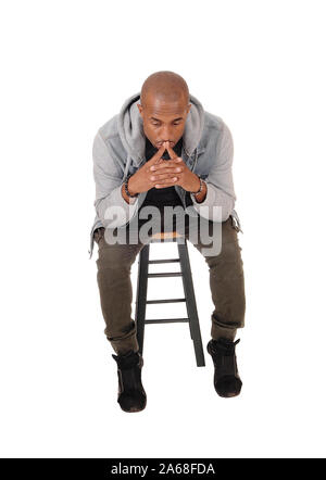 A young handsome African American man sitting on a chair with his fingers on his mouths, thinking, isolated for white background Stock Photo