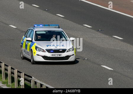 A police patrol vehicle, Peugeot 308 Access SW Blue HDI S/, traveling on the M6 motorway near Preston in Lancashire, UK Stock Photo