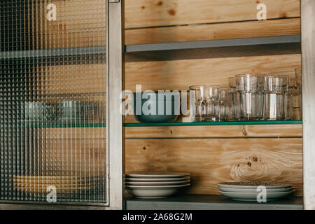 Clean plates and glasses on a shelf in the closet. Stock Photo