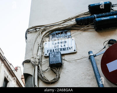 Barcelona, Spain - Nov 16 2017: Low angle view of Carrer de la Fraternitat street name translated as Street of Fraternity and multiple cables for internet and electricity Stock Photo