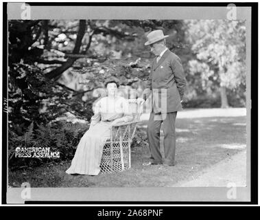 Woodrow Wilson, full-length portrait, standing next to his wife, Ellen, seated in a chair Stock Photo