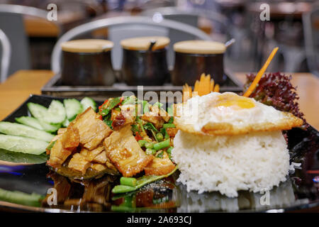 Close up view of  Thai spicy Basil with crispy belly pork, Yardlong Bean and red chili serve with streamed rice and fried egg. Stock Photo