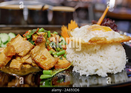 Close up view of  Thai spicy Basil with crispy belly pork, Yardlong Bean and red chili serve with streamed rice and fried egg. Stock Photo