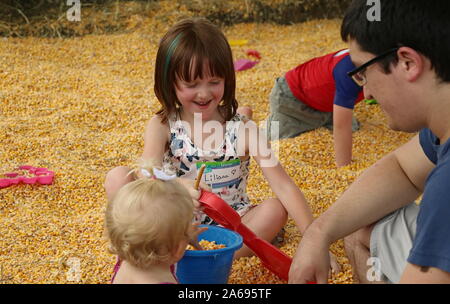 Verona, WI / USA - June 16, 2018: Father and smiling daughters play in a corn pit Stock Photo
