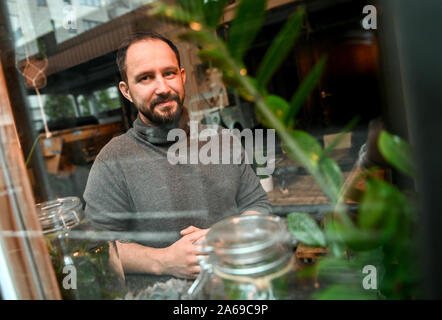 Berlin, Germany. 24th Oct, 2019. Christian Otto, operator of the café 'The Greens' looks through the window. (To Korr ' Green and chic: Young city dwellers let plant market boom' of 25.10.2019) Credit: Britta Pedersen/dpa-Zentralbild/dpa/Alamy Live News Stock Photo