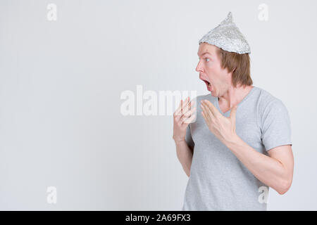 Profile view of young man with tinfoil hat looking shocked Stock Photo