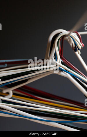 Colourful coat hanging bunched together on indoor clothing horse. Stock Photo