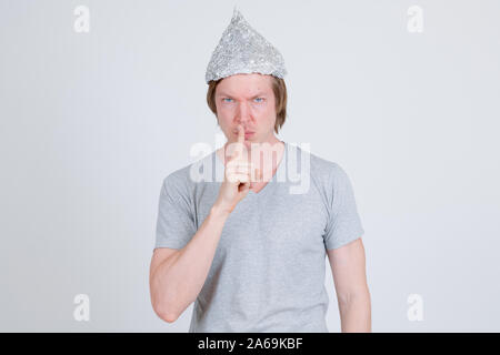 Young man with tin foil hat with finger on lips