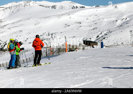 PYRENEES, ANDORRA - FEBRUARY 13, 2019: Group skiers stand at the beginning of the ski slope and look down. Pyrenees, Andorra, winter sunny day, copysp Stock Photo