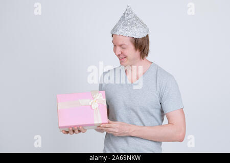 Happy young man with tin foil hat holding gift box Stock Photo