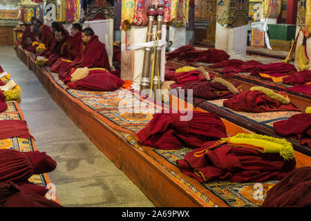 Buddhist monks of the Yellow Hat Sect or Gelug sect worshipping in Coqen Hall in the Ganden Buddhist monastery near Lhasa, Tibet. Stock Photo
