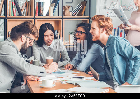 Startupers working together at office sitting discussing chart laughing cheerful Stock Photo