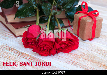 Old books and red rose, traditional gift for Sant Jordi, the Saint Georges Day. Catalunya's version of Valentine's day.Phrase Happy Saint Georges in c Stock Photo