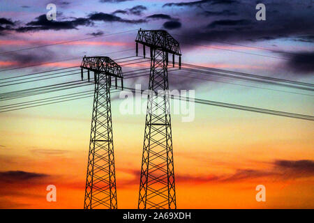 High voltage power lines sunset pylons transmission energy Germany Global warming sky Stock Photo