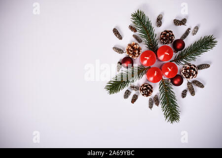 Christmas New Year composition. Seasonal greeting card concept with red advent candles, evergreen branches and pinecones, on white background. Stock Photo