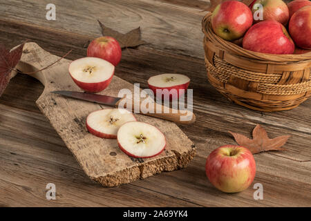 sliced apples on a wooden cutting board on a table decorated with leaves for autumn Stock Photo